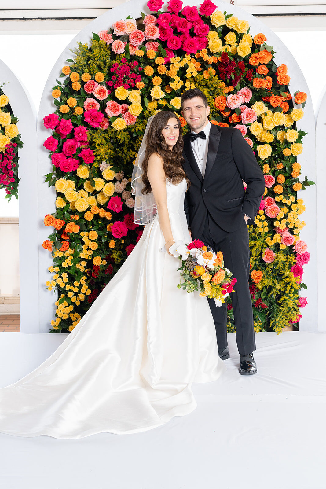 Bride and groom in front of a colorful floral arch at Surf Club on the Sound