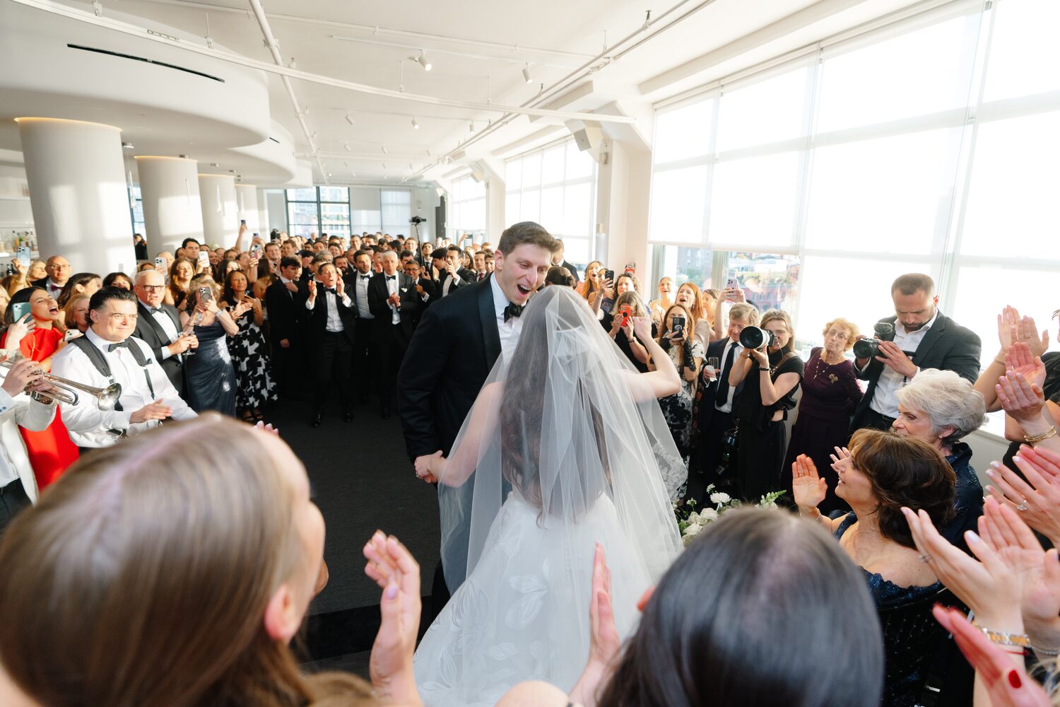 Veiled for the bedeken, the bride moves through a corridor of clapping guests.