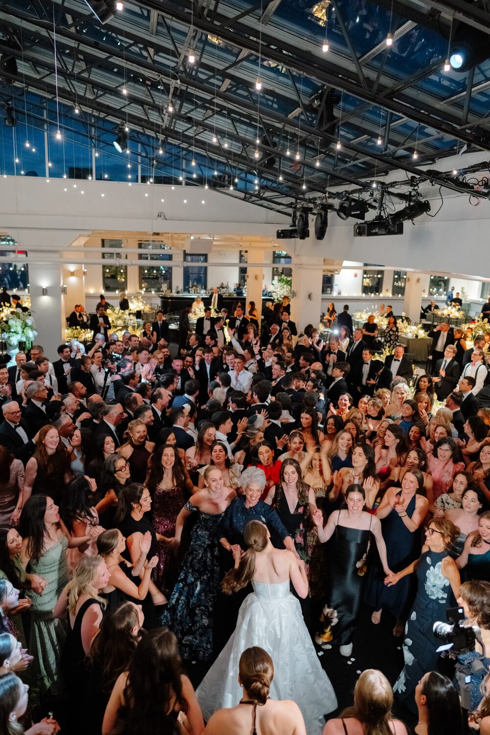 The bride dances at the center of a packed floor, guests pressing in around her.