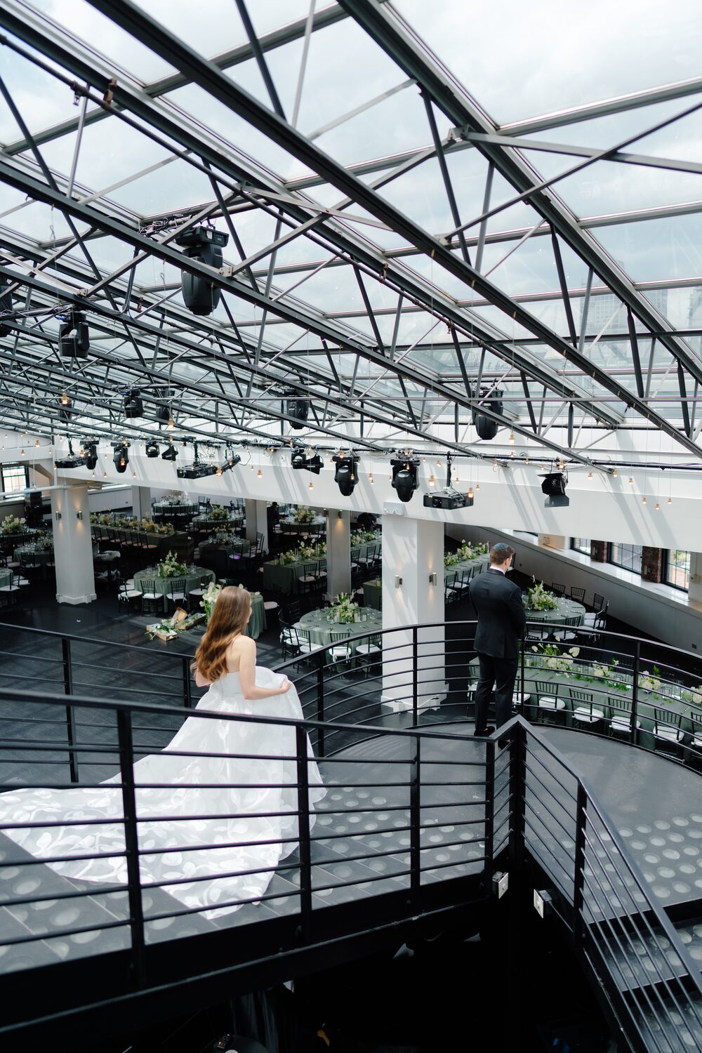 The bride looks down over the reception from the mezzanine railing.