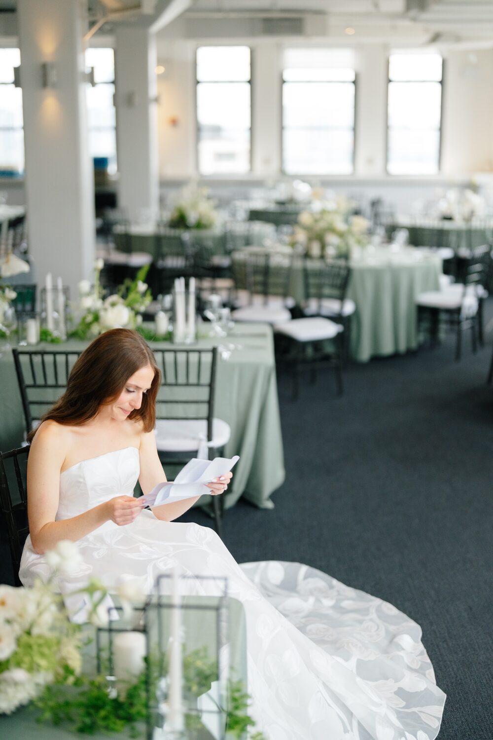 The bride sits alone in the quiet reception room reading a letter before the ceremony begins.