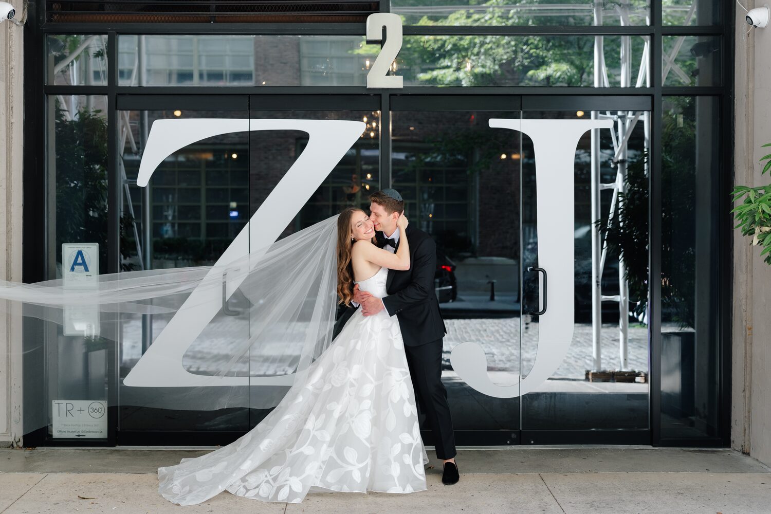 The couple kisses at the Tribeca Rooftop entrance beneath oversized Z and J monogram letters.