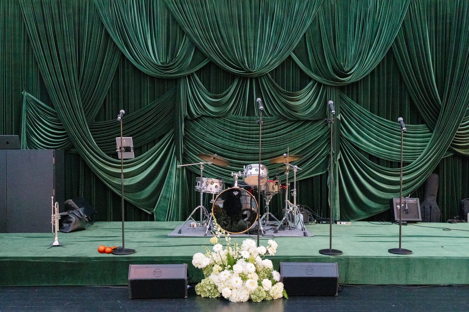The green velvet band stage sits ready with drums and microphones before guests arrive.