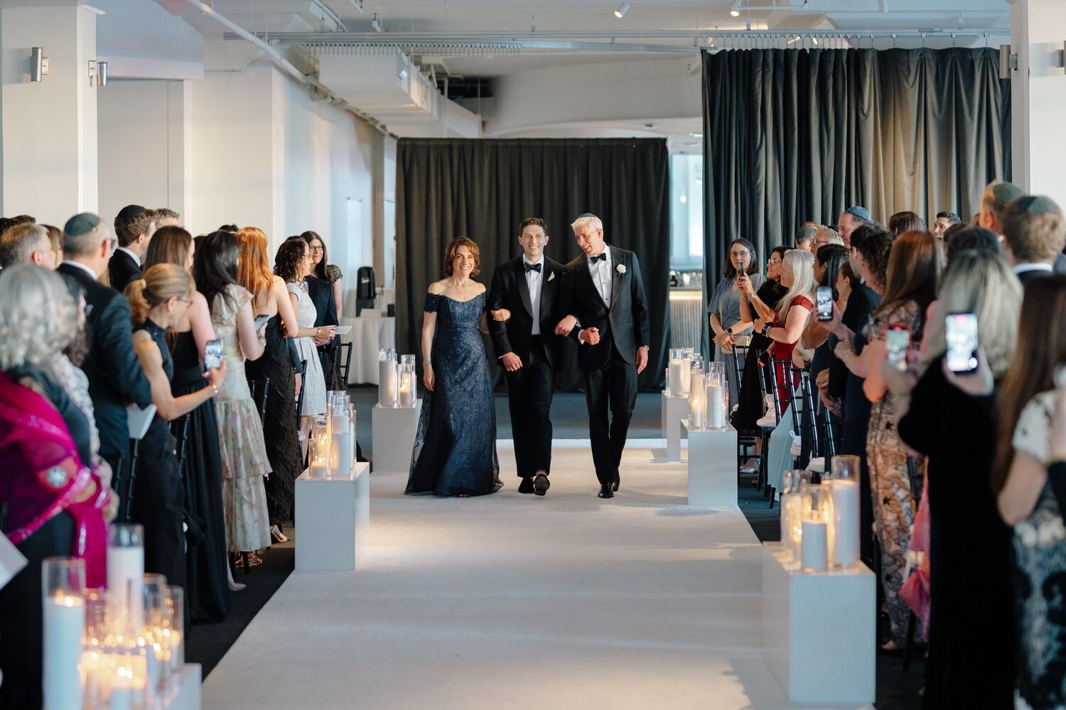 Parents make their way down the candlelit aisle ahead of the ceremony.