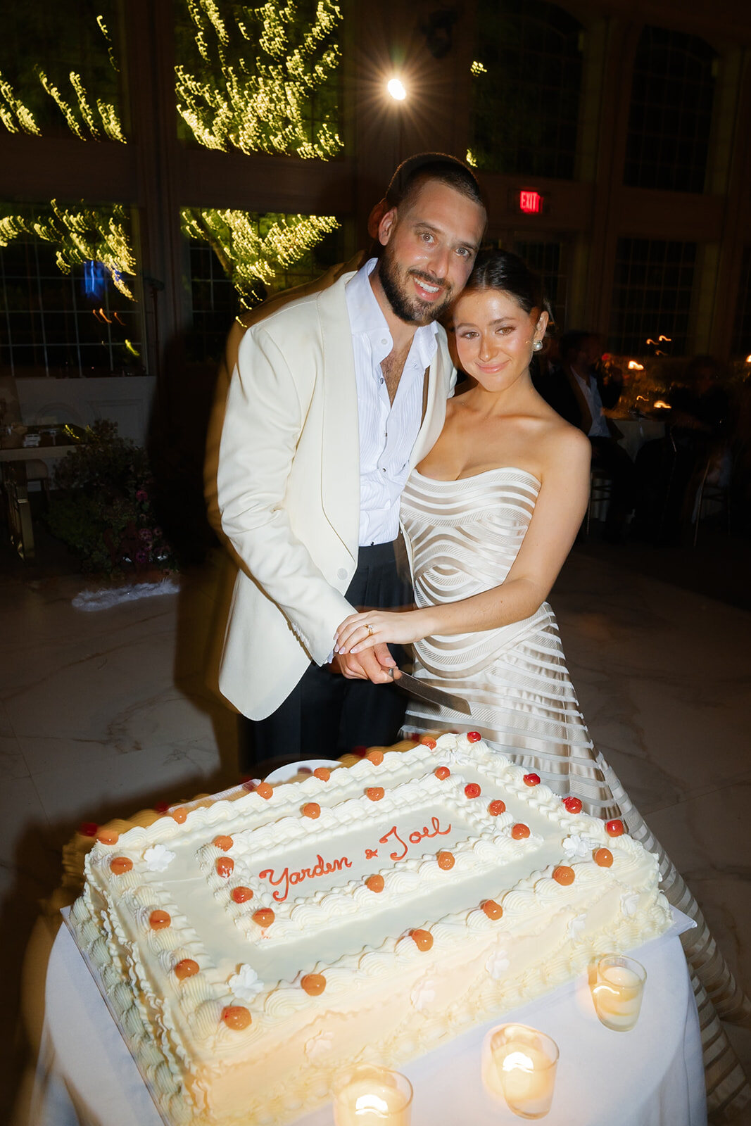 Yarden and Joel laugh as they cut their wedding cake