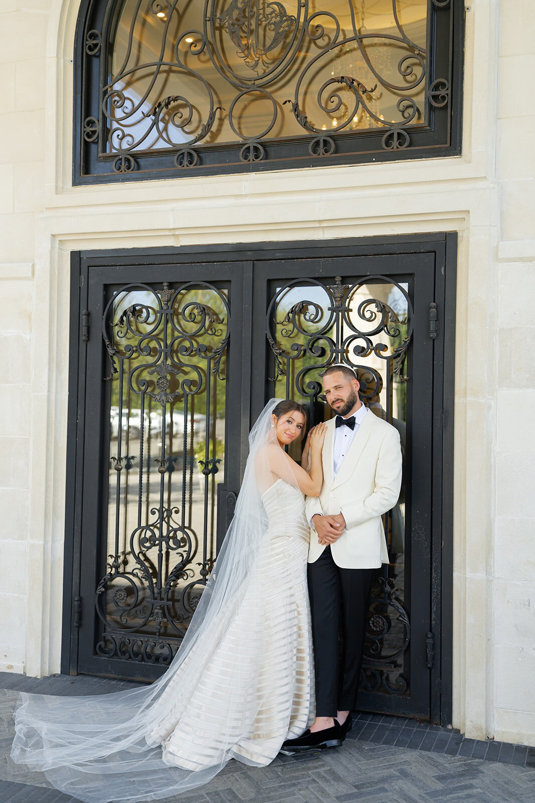 Yarden and Joel at the estate’s wrought-iron doors, her cathedral veil pooling on the steps