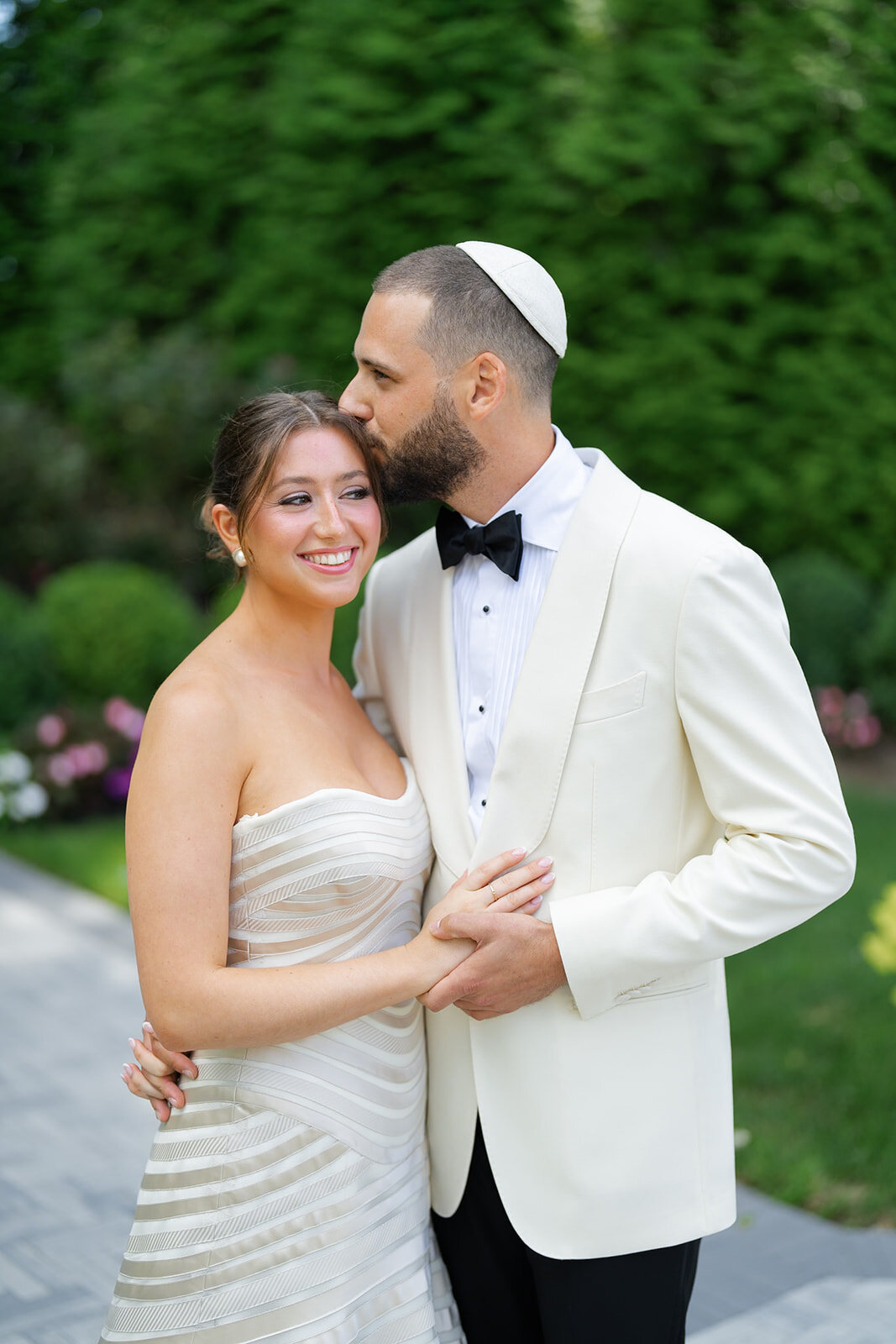 Joel in a white kippah kisses Yarden’s forehead in the formal gardens
