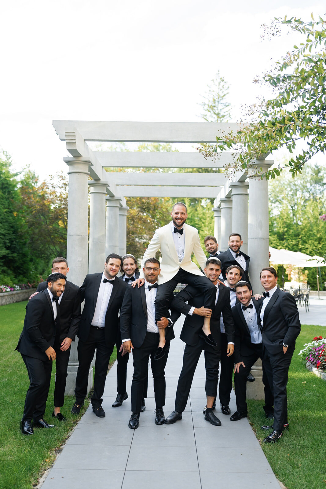 Joel’s groomsmen lift him into the air on the pergola walk