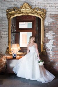 Bridal portrait beside a gilded mirror and exposed brick at the Liberty Warehouse