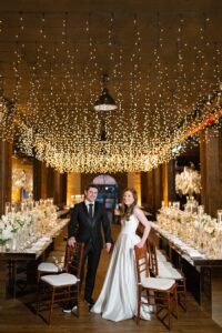 Bride and groom beneath the string light canopy in the Liberty Warehouse reception room