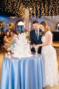 Cake cutting under string lights at a Liberty Warehouse wedding reception