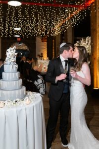 Bride and groom kiss beside their wedding cake with champagne at the Liberty Warehouse