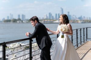 Couple at the harbor railing with the Manhattan skyline, morning portrait at the Liberty Warehouse
