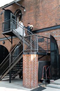 Bride and groom on the steel staircase against the brick facade of the Liberty Warehouse, Red Hook