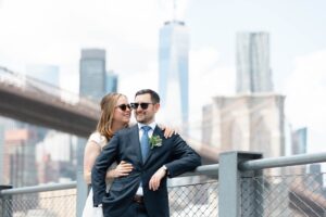 Bride and groom in sunglasses beneath the Brooklyn Bridge in DUMBO