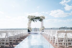 Mirrored aisle and white floral chuppah set for a harbor-side ceremony at the Liberty Warehouse