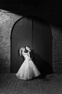 Night dip kiss at the arched warehouse door, black and white, Red Hook