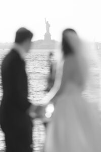 Bride and groom on the Red Hook pier with the Statue of Liberty in the distance, black and white